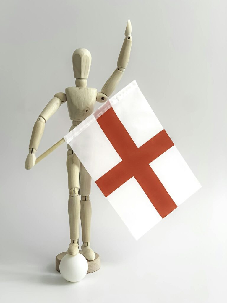 A wooden mannequin celebrates holding an England flag, symbolizing patriotism and support.